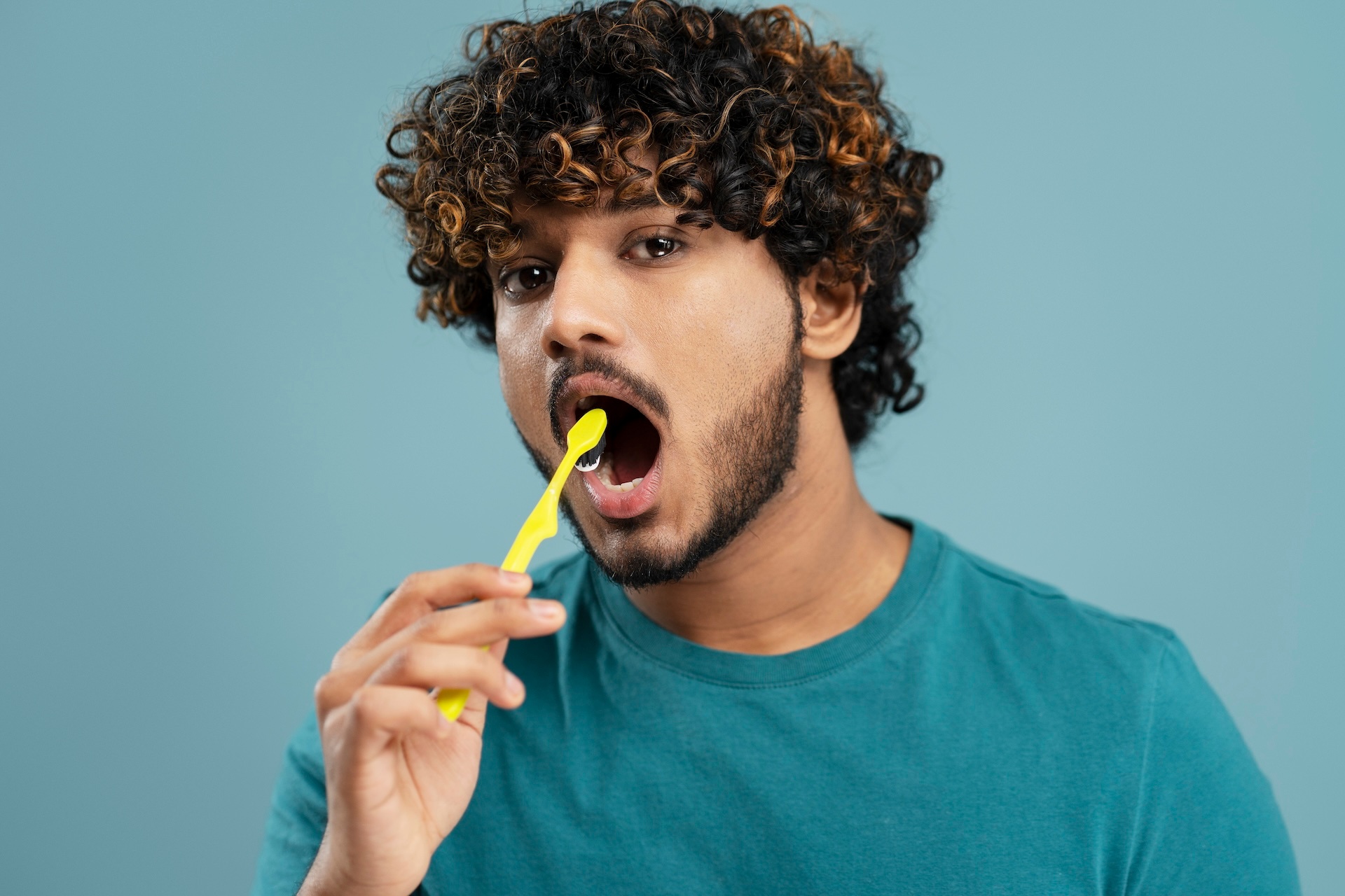 handsome-asian-young-man-brushing-teeth-with-a-yel-2023-11-27-04-53-41-utc