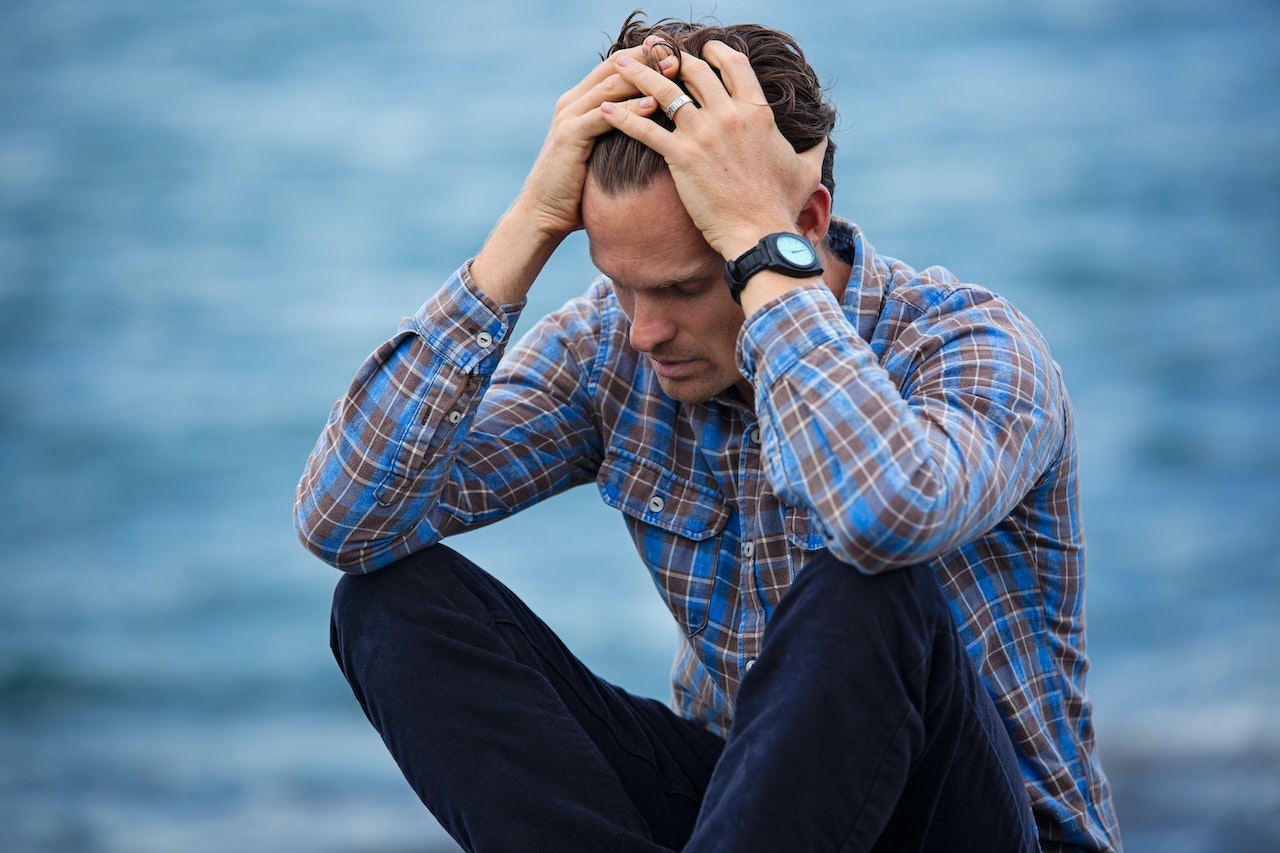 FORGE Depression-addiction-connection-dual-diagnosis Photo of a depressed young man holding his head in his hands.