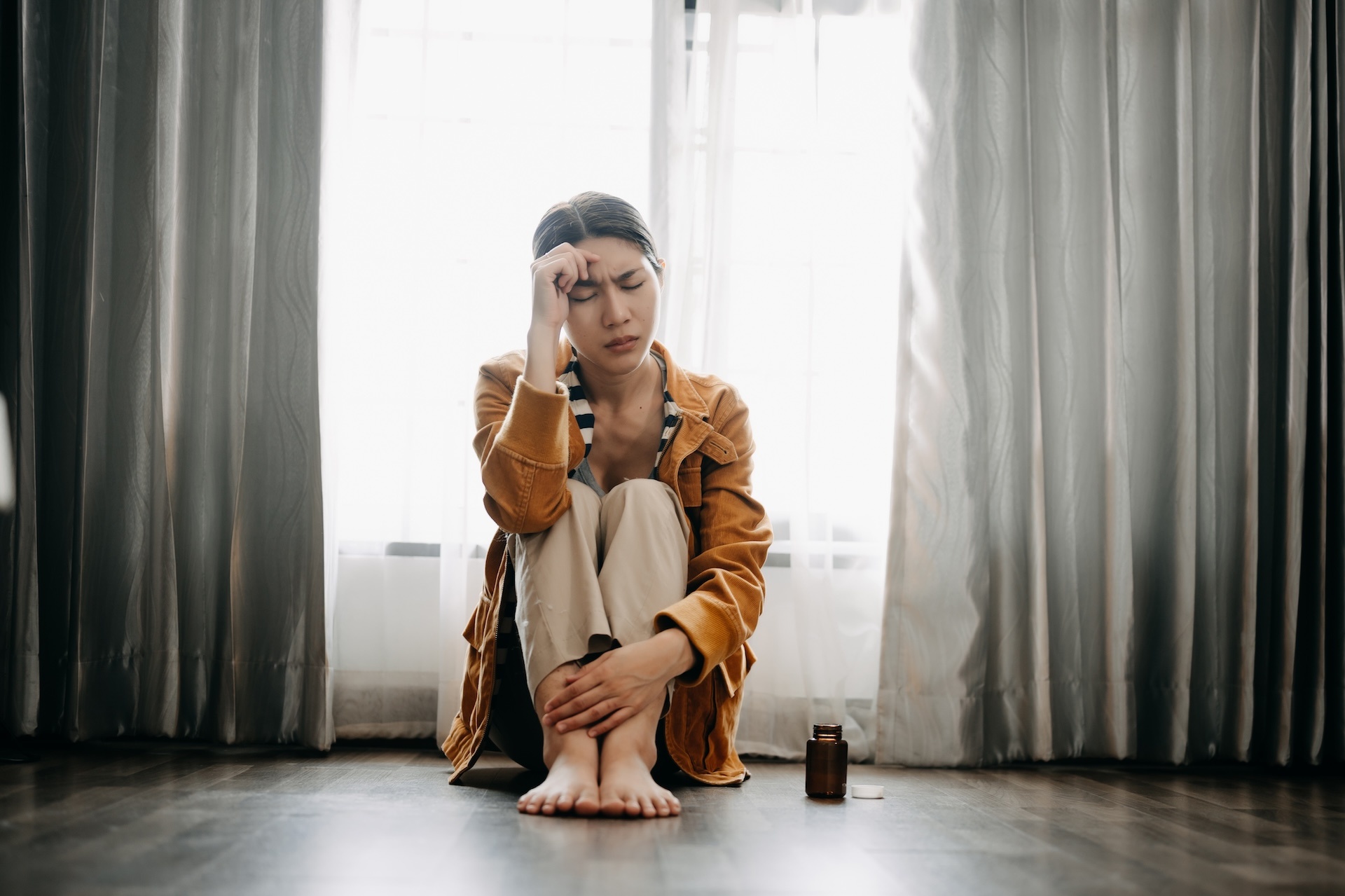 Oxycontin addiction victim woman sitting on the floor from withdrawal effects