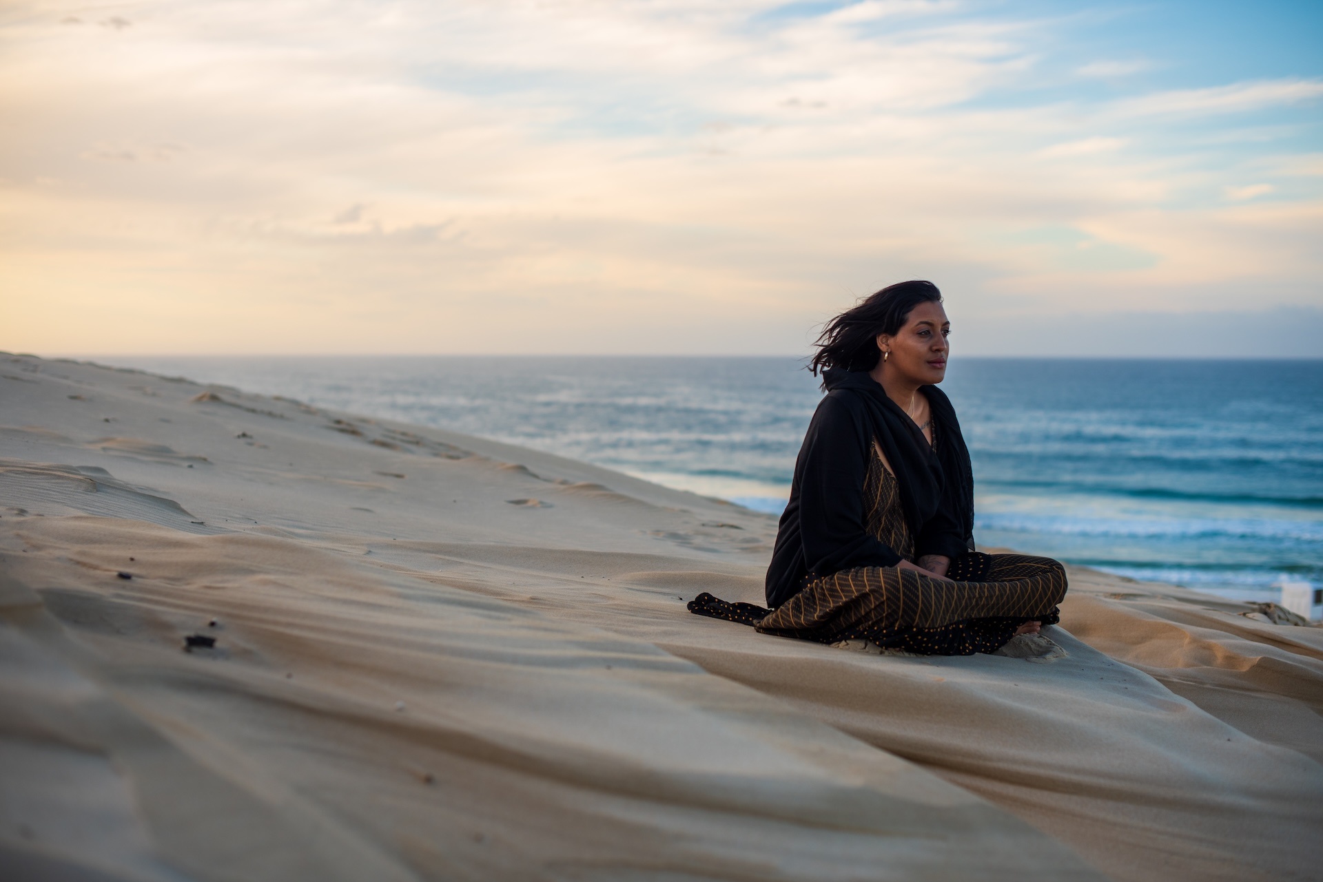 woman-seen-sitting-on-sand-dune-while-watching-the-2025-01-07-09-49-25-utc