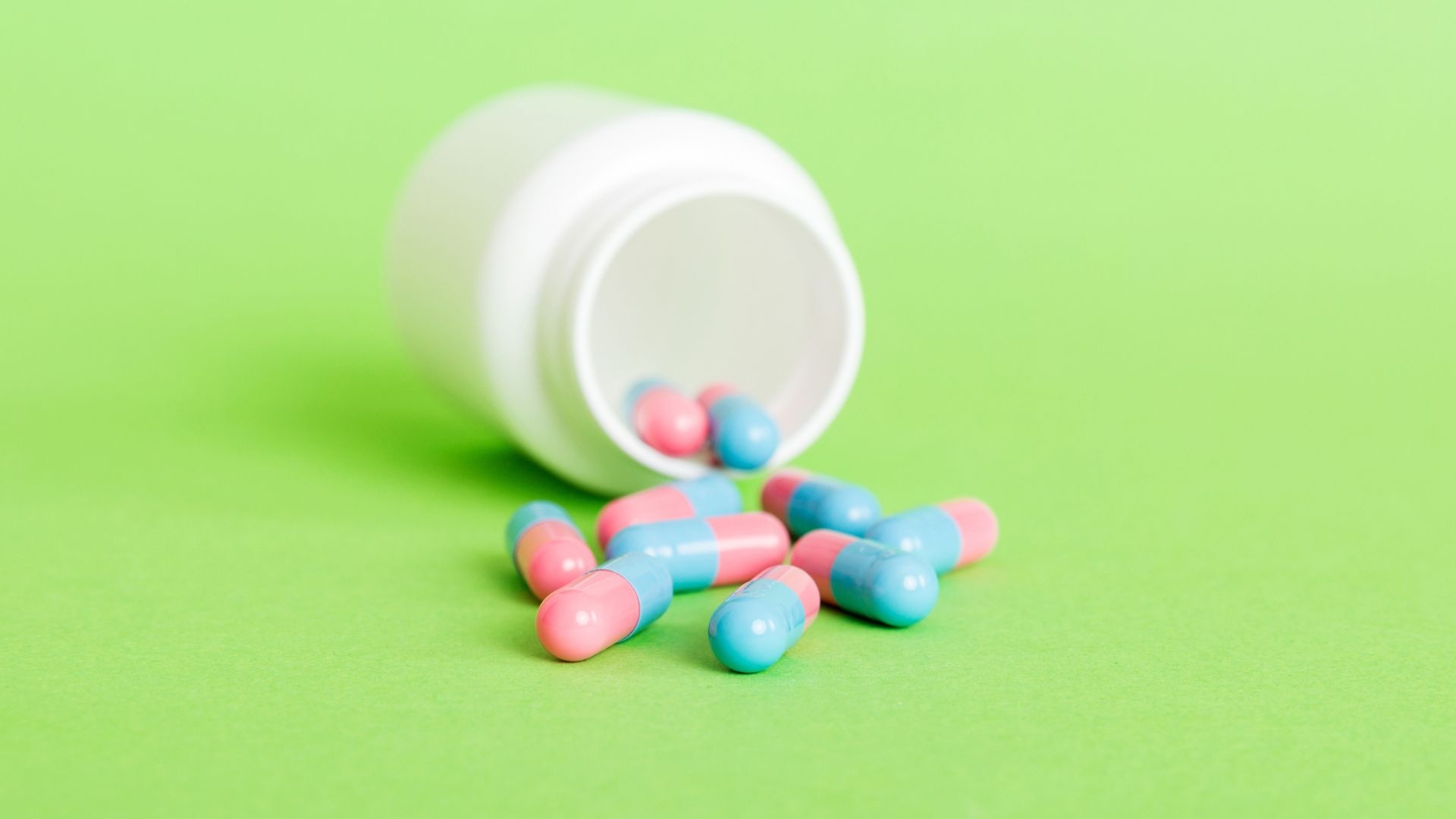 Phentermine Addiction pills dropped on a green surface Phentermine Addiction pills dropped on a green surface