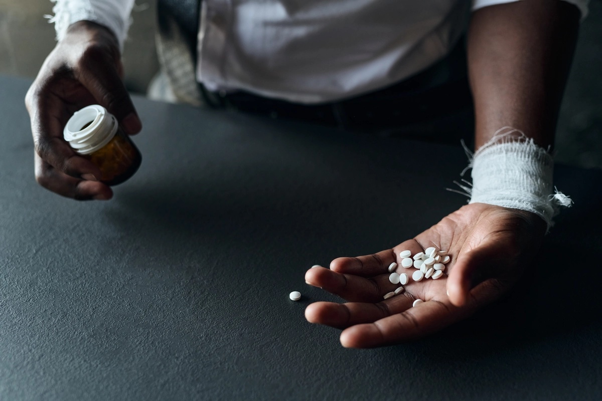 A man struggling with prescription drug addiction poses with pills and a pill bottle in his hands. A man struggling with prescription drug addiction poses with pills and a pill bottle in his hands.