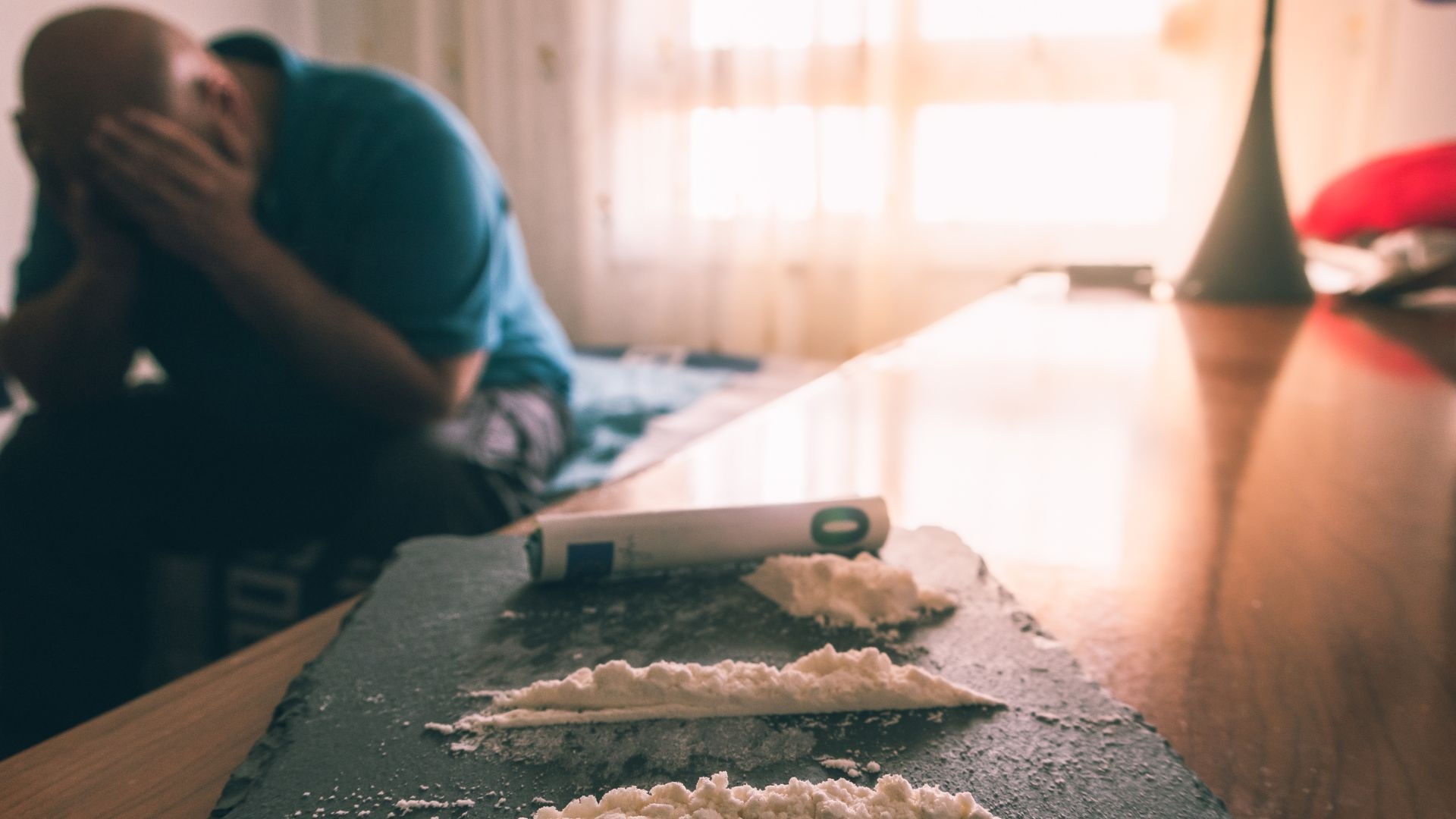 Coke addiction: Sad man next to piles of cocaine. Coke addiction: Sad man next to piles of cocaine.