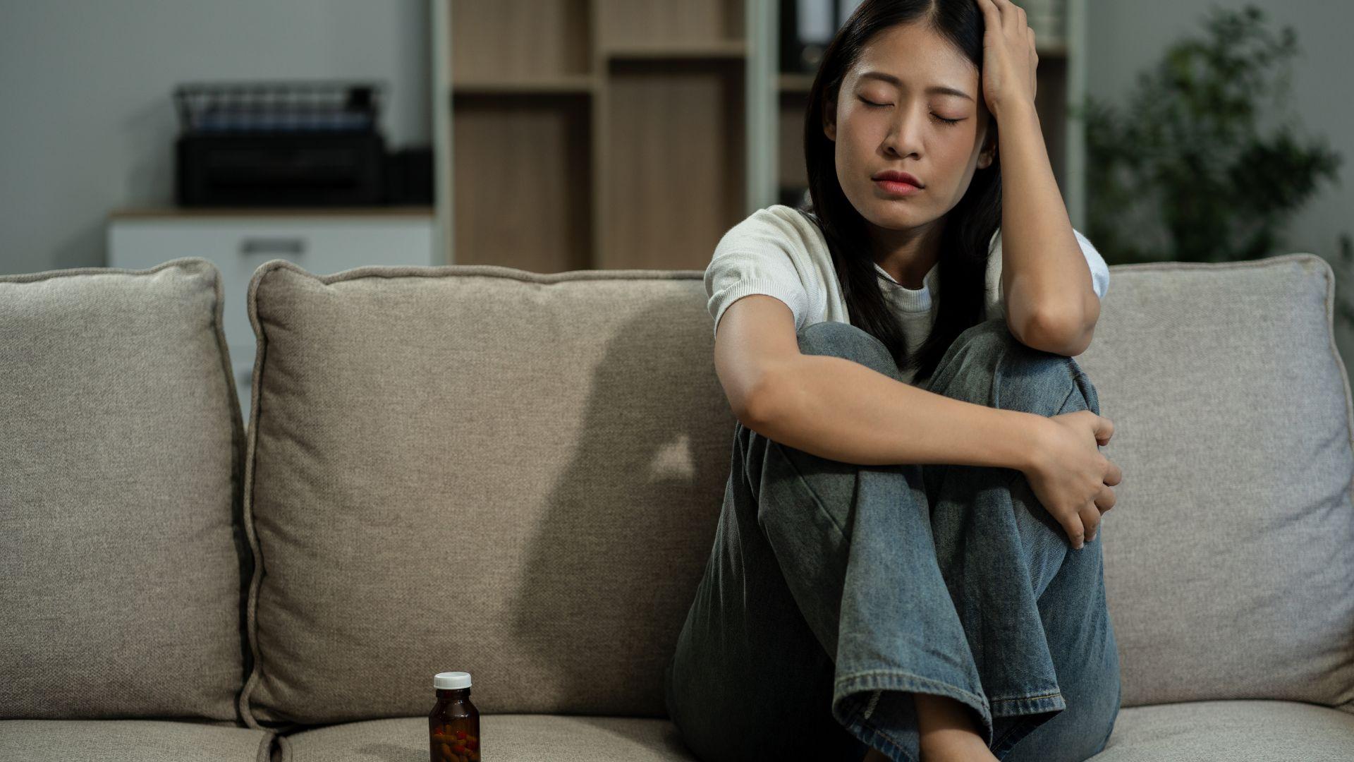 Cortisol Addiction - woman sitting on couch with a headache