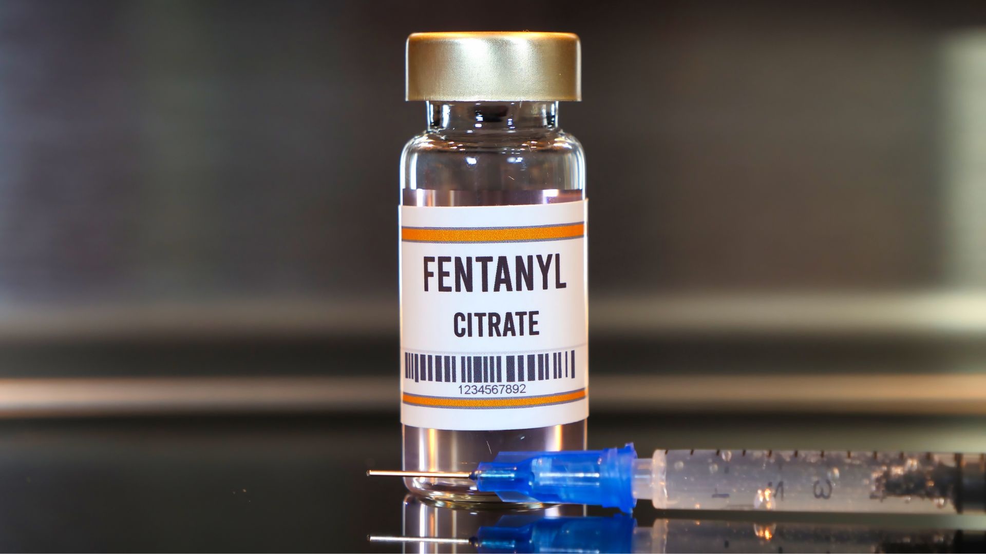 Fentanyl drug and syringe on black table with reflections and stainless background Fentanyl drug and syringe on black table with reflections and stainless background