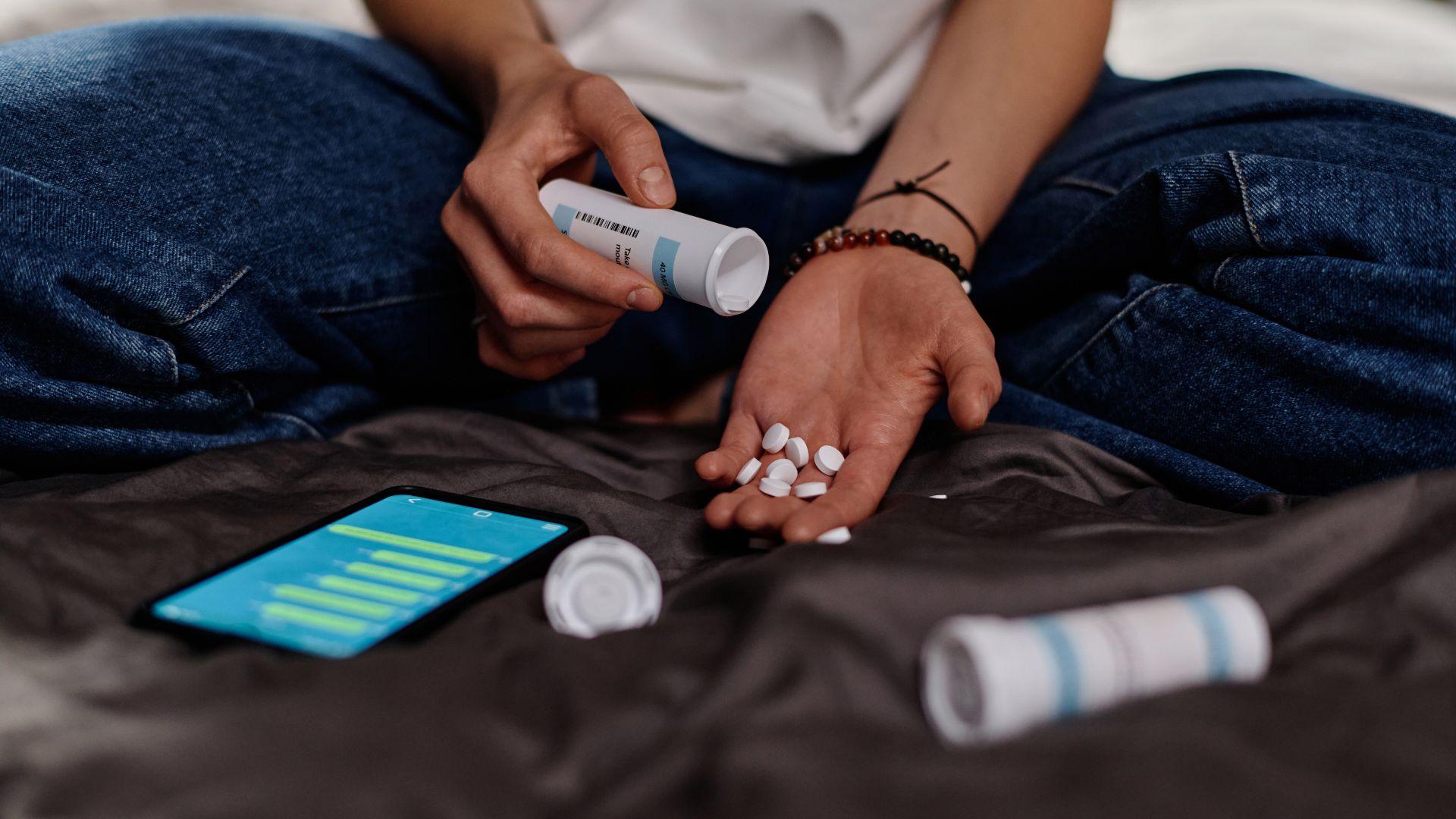Oxycontin symptoms: man with hand full of of oxycontin pills.
