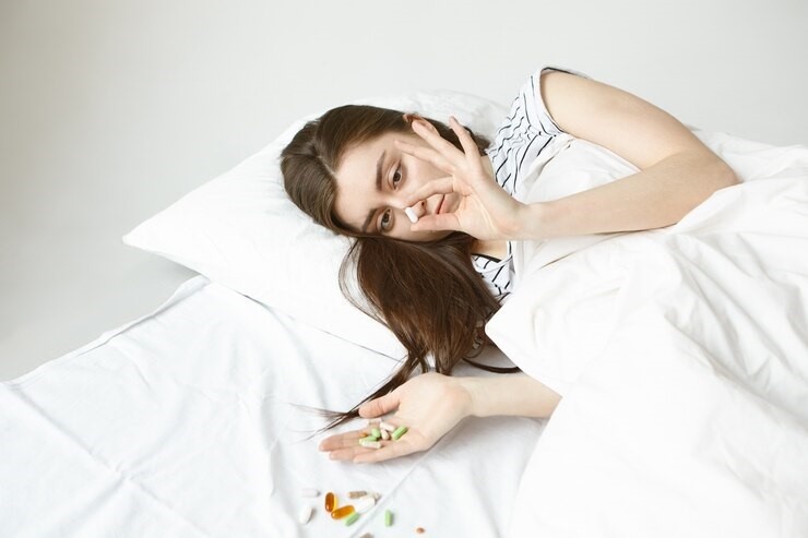 DAS FORGE Xanax-Addiction Woman in bed near pills. She's also holding pills.