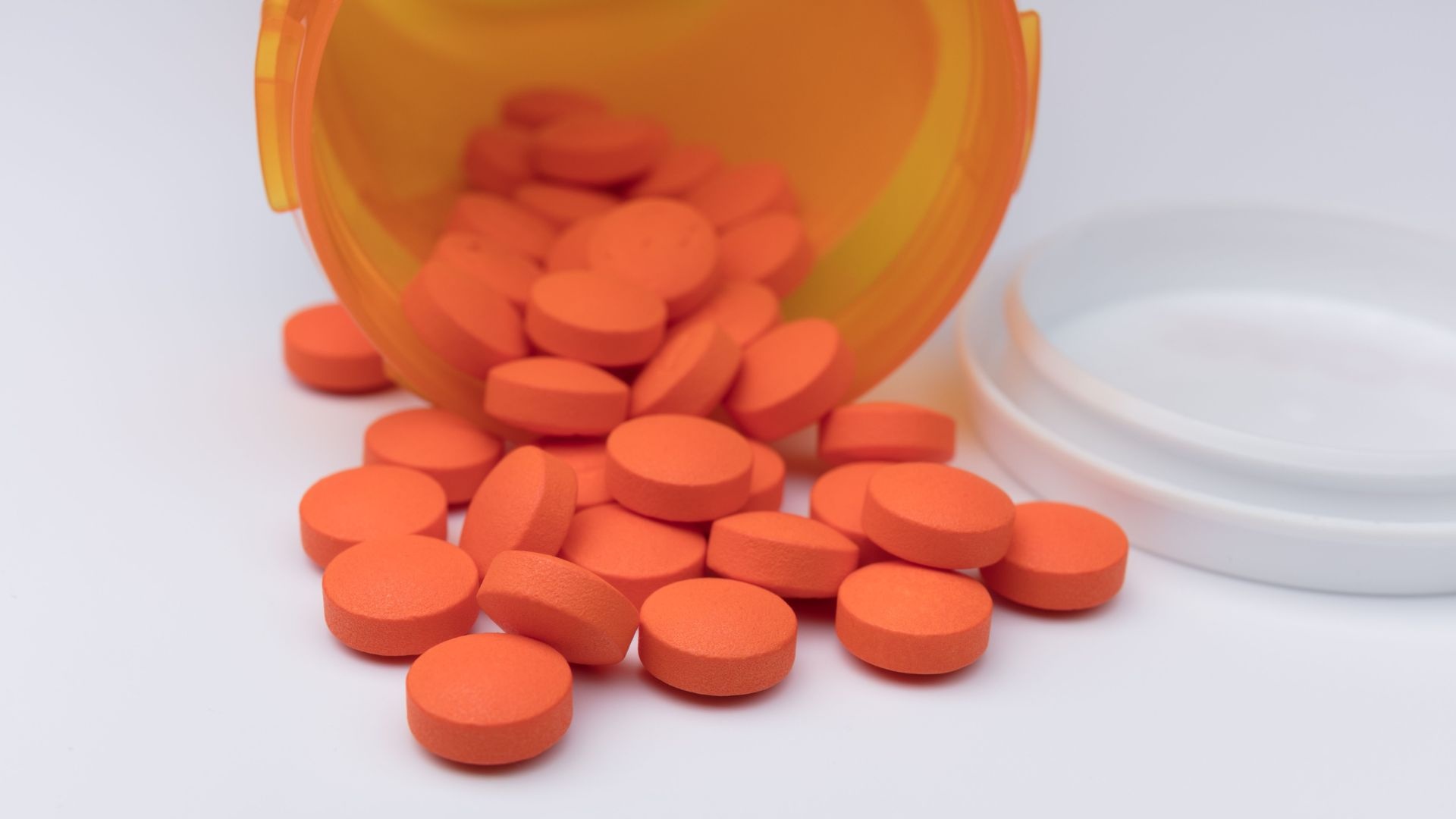 Ibuprofen addiction: bottle of ibuprofen spilled showing pile of ibuprofen pills. Ibuprofen addiction: bottle of ibuprofen spilled showing pile of ibuprofen pills.