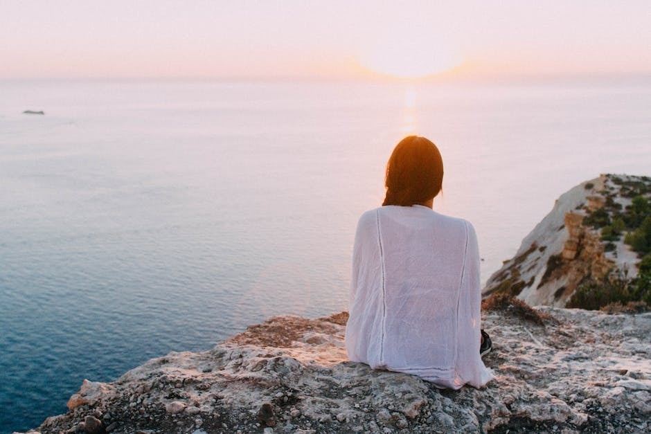 Dual Diagnosis: Does Drug Detox Address Mental Health Issues? Photo of a woman sitting on a cliff overlooking the ocean.