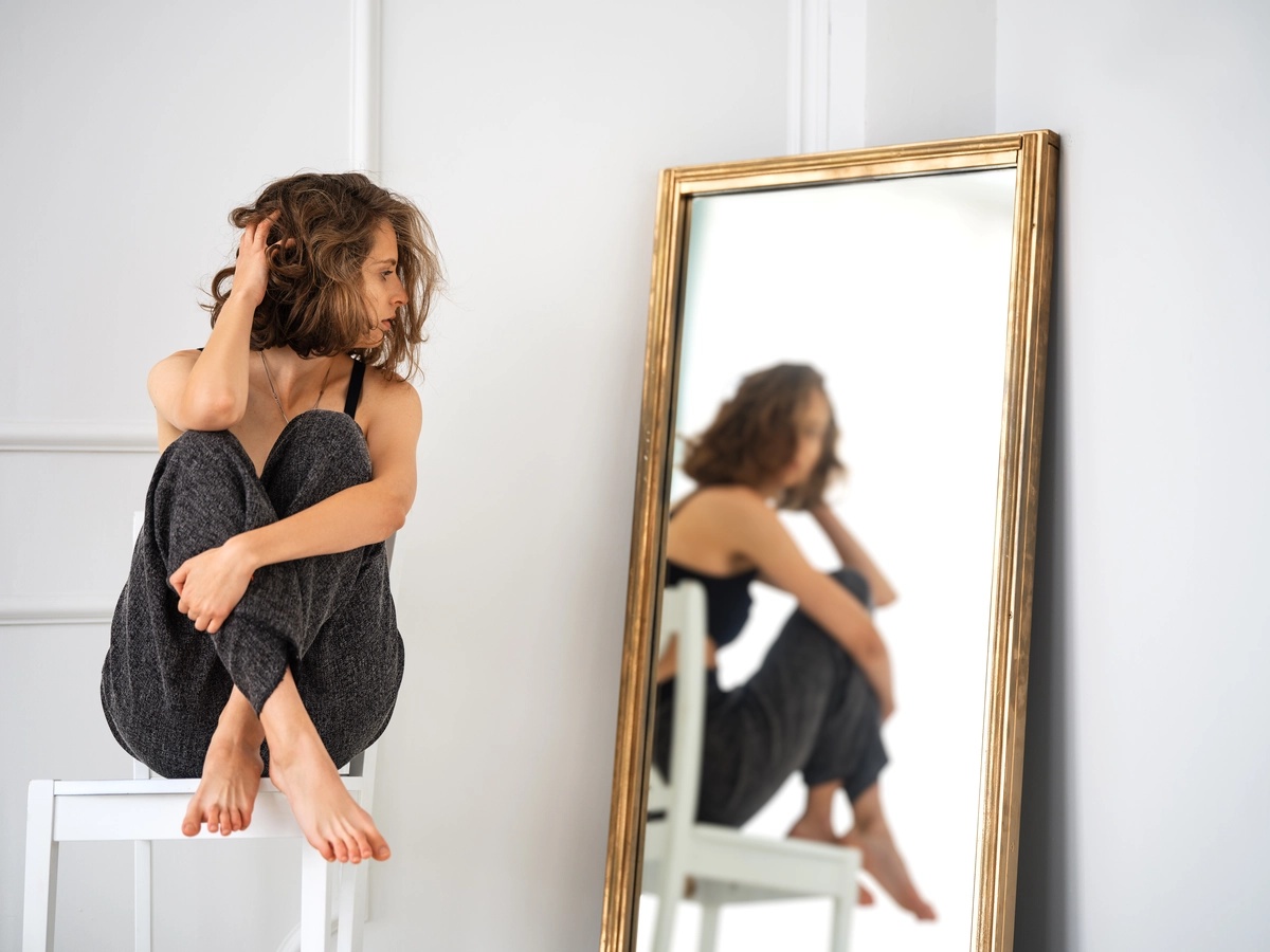Histrionic personality disorder A woman sitting on a table stares at herself in a mirror.