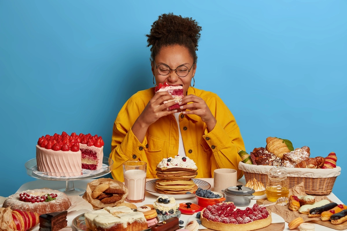 A woman, potentially with a food addiction, eating a large platter of desserts. A woman, potentially with a food addiction, eating a large platter of desserts.
