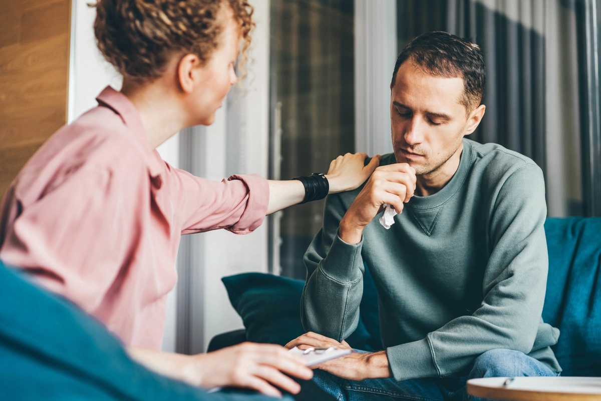 A therapist comforts her patient, putting her hand on his shoulder during drug rehab in Orange County, CA. A therapist comforts her patient, putting her hand on his shoulder during drug rehab in Orange County, CA.