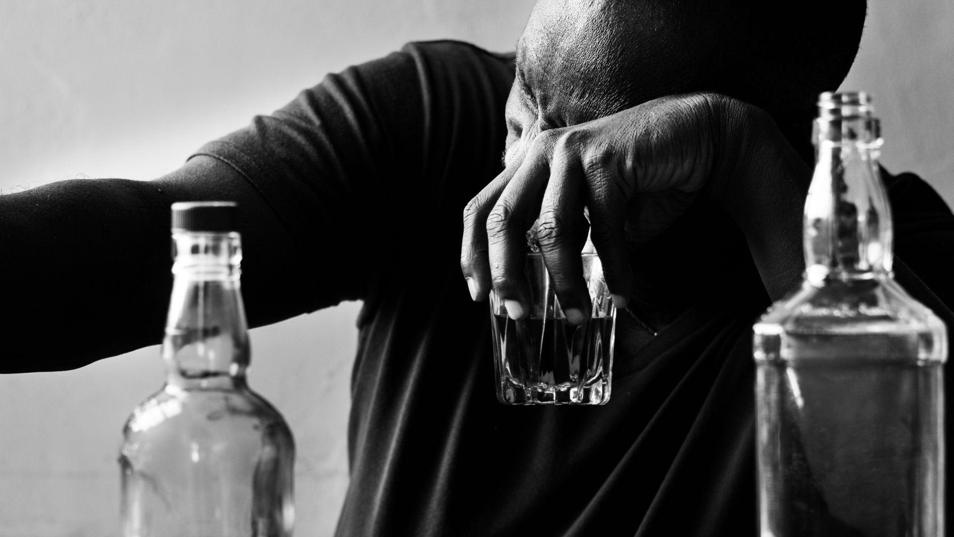 Alcohol treatment first steps: picture of man drinking and crying at a bar.
