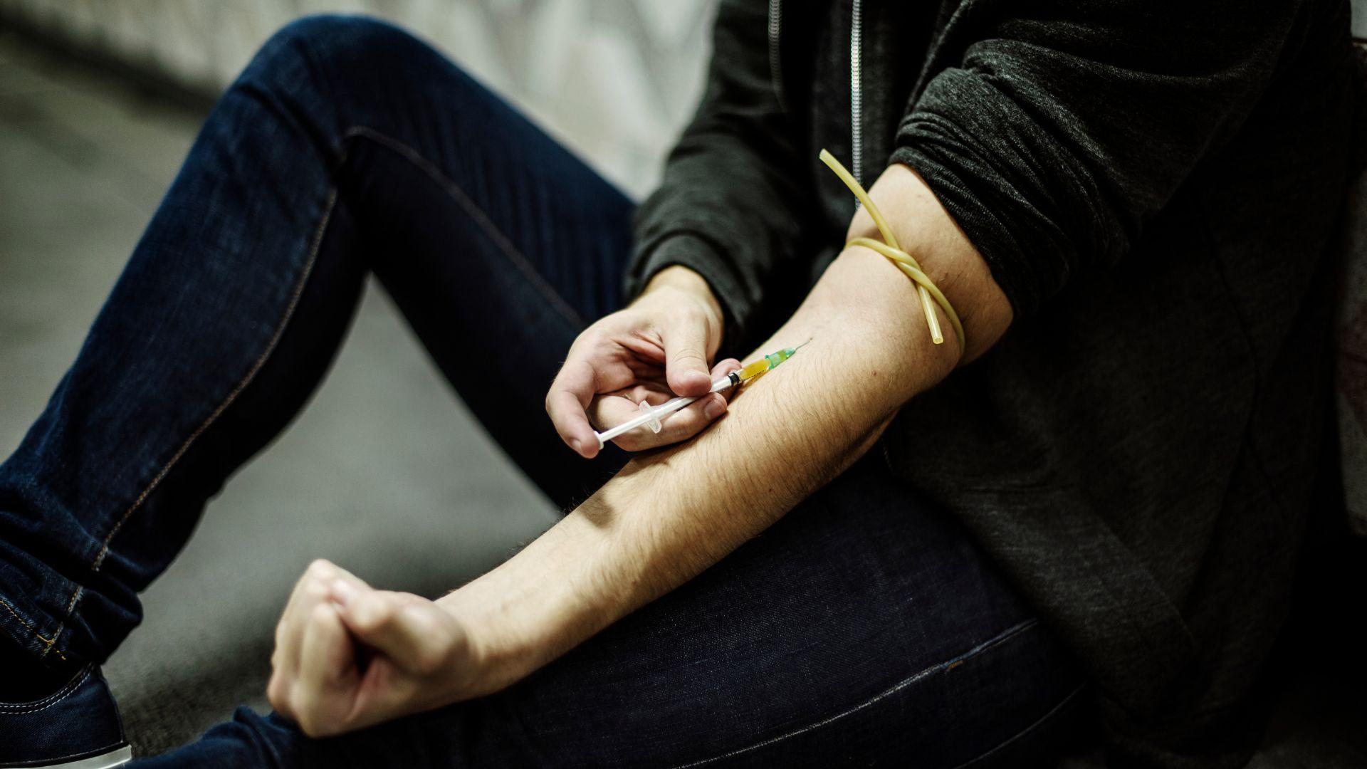 Heroin addiction symptoms: man injecting heroin into arm.