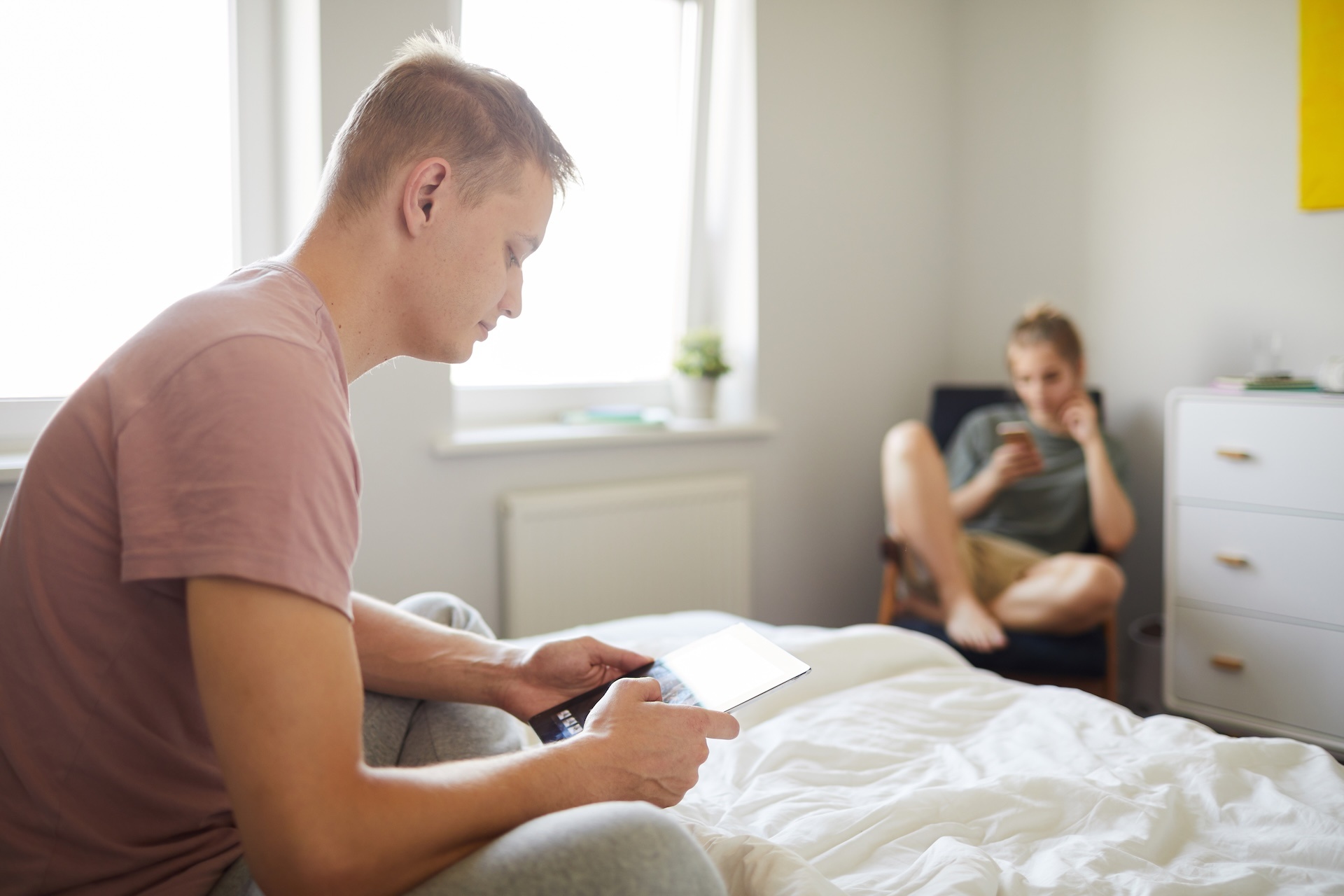 contemporary-guy-with-mobile-gadget-sitting-on-bed
