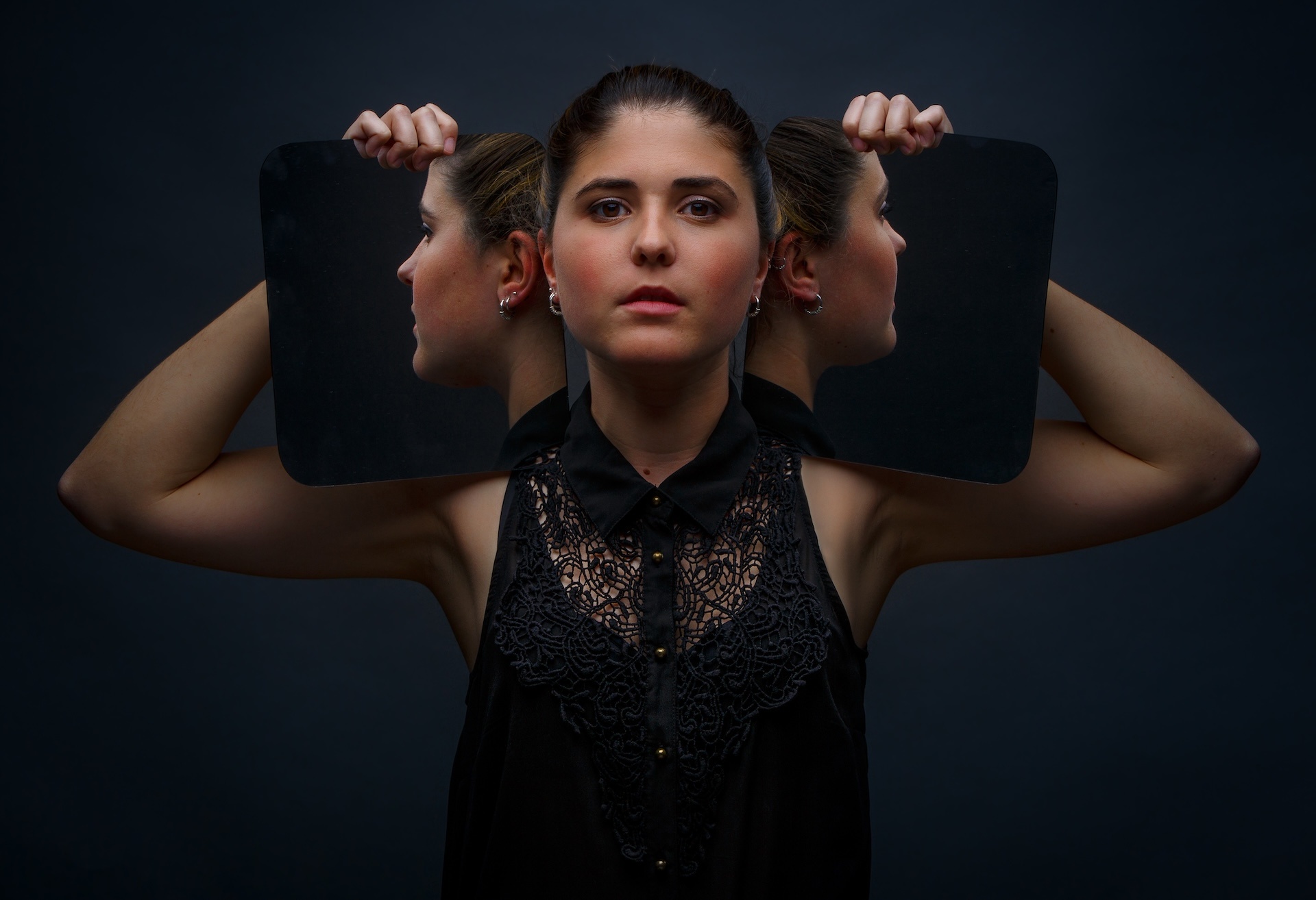 modern-model-holding-mirrors-on-sides-of-face-2025-04-03-15-41-24-utc