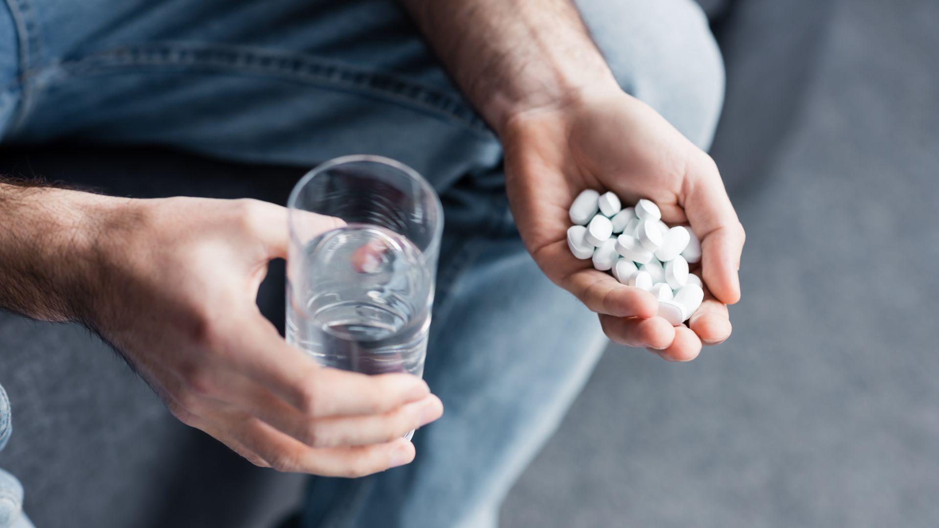Oxycontin addiction: man holding multiple Oxycontin pills.