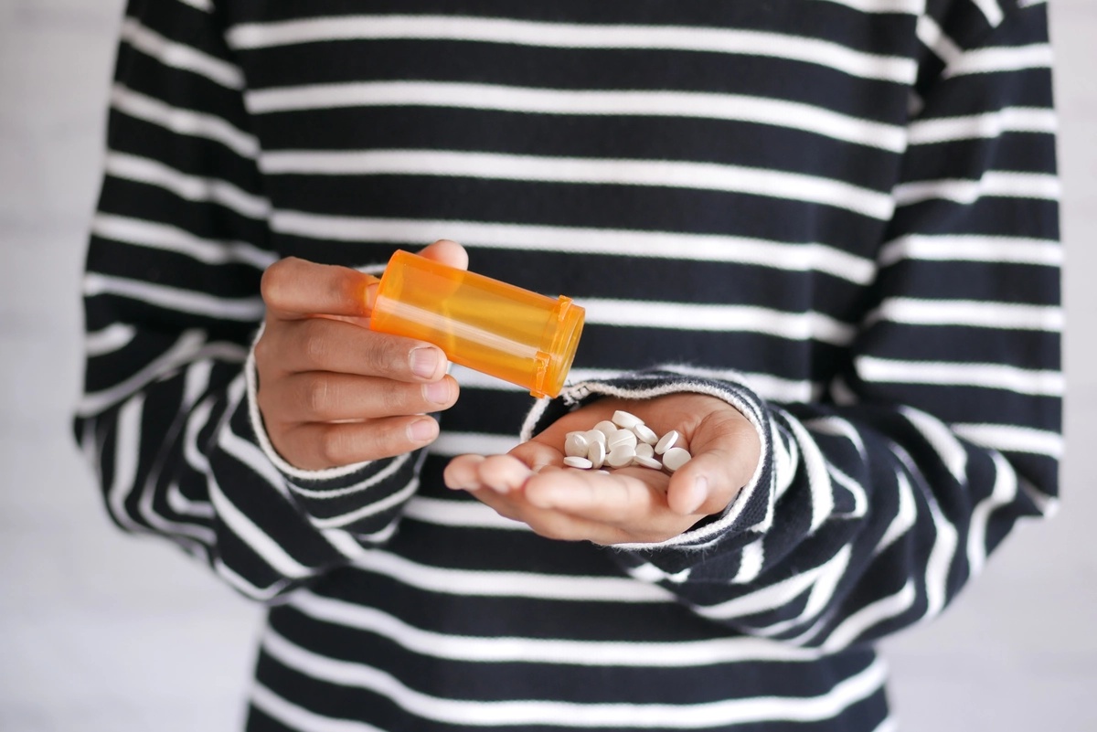 A person dealing with synthetic drug addiction pours some pills into their hand. A person dealing with synthetic drug addiction pours some pills into their hand.