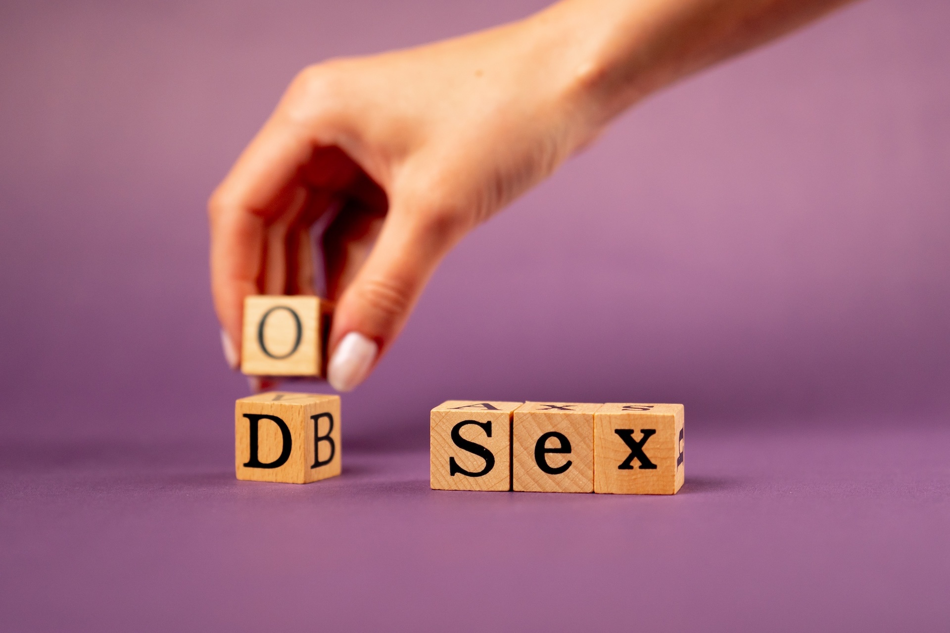 violet-warm-background-with-shadows-woman-hand-with-letter-dice-spelling-sex
